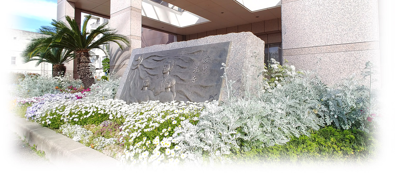 施設入口周辺の庭園。装飾的な石彫と季節の花が美しく配置されている。